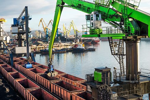 Powerful hydraulic crane - manipulator unloads cars in the industrial port.
