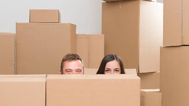 happy couple surounded by cardboard boxes only seeing half of their heads