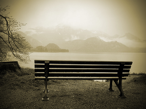 bench at a lake with Alpen in background, mobile phone