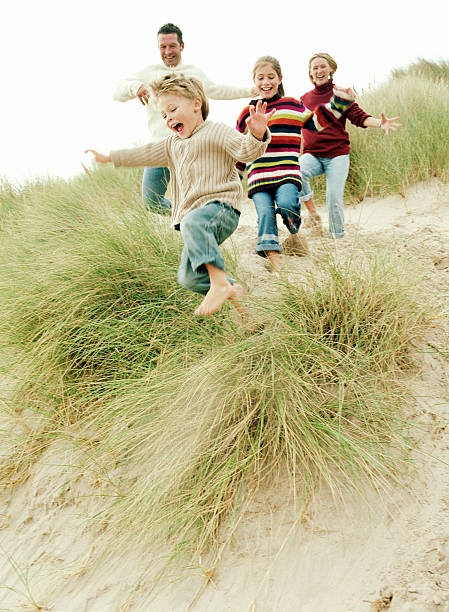 Family running down a grassy hill