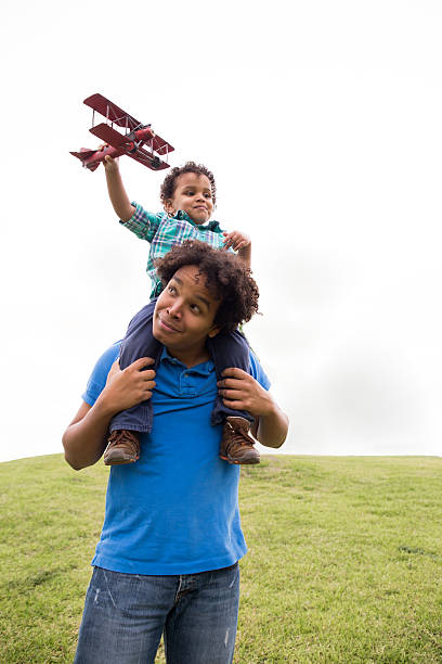 Father playing with cute son at the park on summer holiday, daddy carrying and lifting boy up to fly. Joyful parent spends time with kid outdoor together in beautiful garden. Happy family, dad and son
