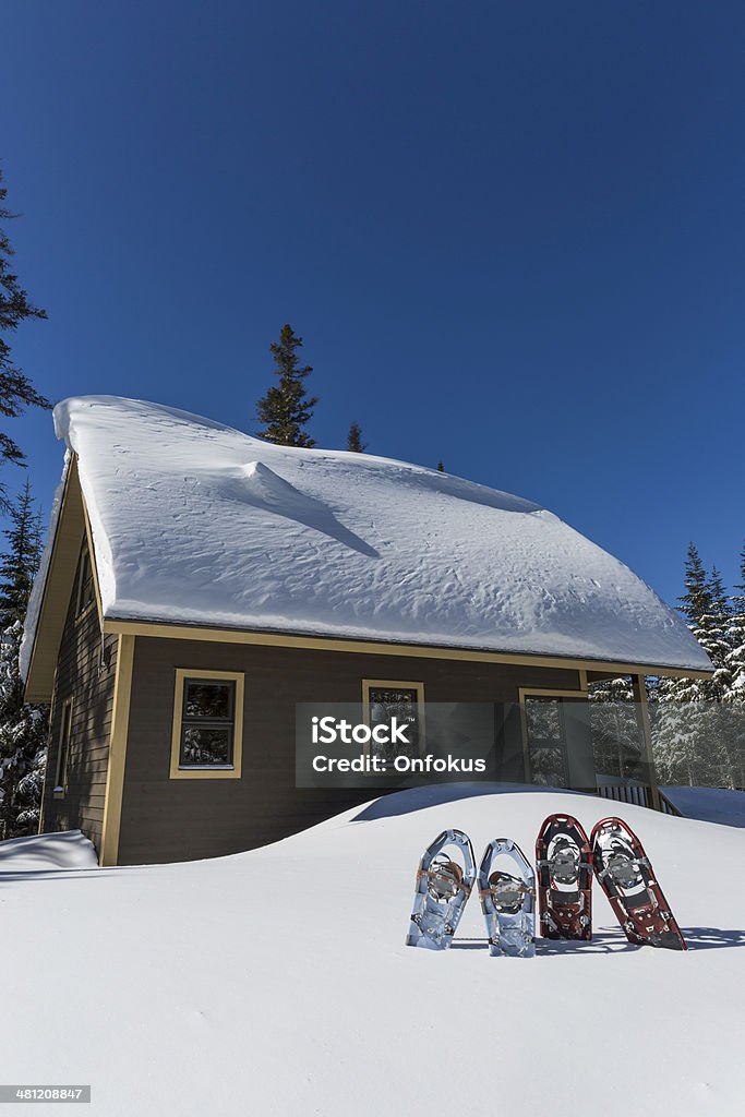 Pairs of Snowshoes Planted in Snow in Front of Chalet Snowshoes and chalet Active Lifestyle Stock Photo