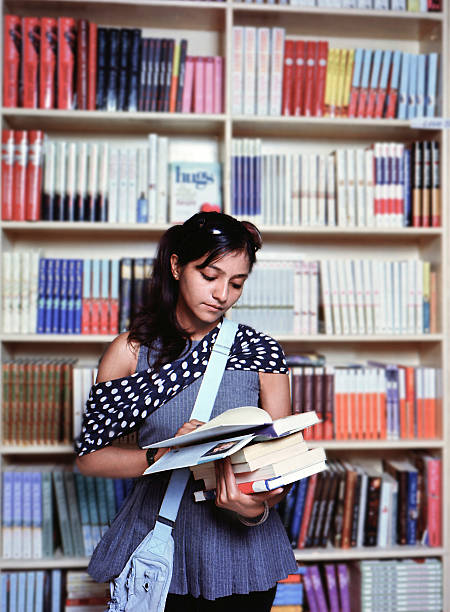 Female student picking a book in University library. Bologna, Italy, Europe