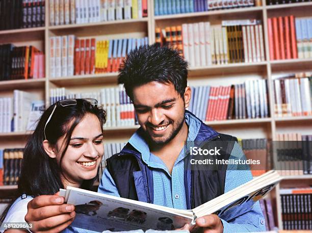 Two Cheerful Youth Studying Book In The University Library Stock Photo - Download Image Now