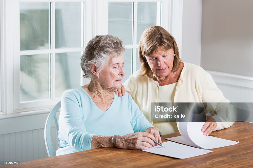 Elderly woman reading paperwork Mature woman (60s) helping elderly mother (90s) with paperwork. Senior Adult Stock Photo