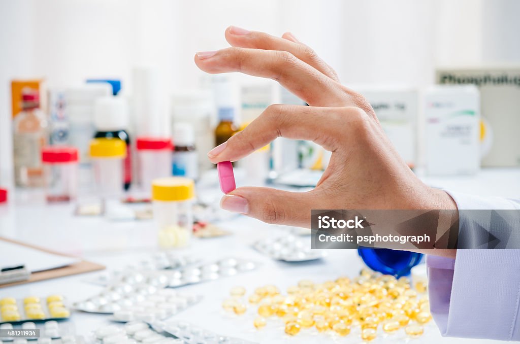 hand holding a pill woman’s hand holding a red pain killer 2015 Stock Photo