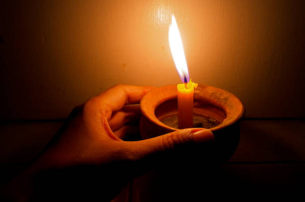 Hand holding a burning candle in pot