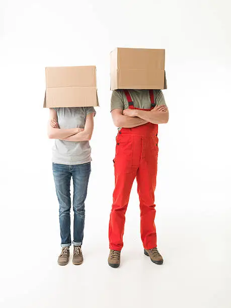 woman and man standing with hands crossed against their chests, hiding their heads under cardboard boxes. on white background