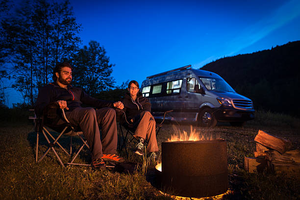 istock Couple Sitting Next to Campfire with Camper Van 481215714