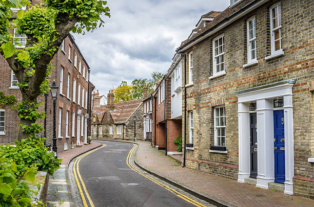 Row fo Terraced Houses in England Terraced houses along a narrow curving street in South-west England. Traditional colourful front doors are visible on the house on the left of the picture. poole harbour stock pictures, royalty-free photos & images