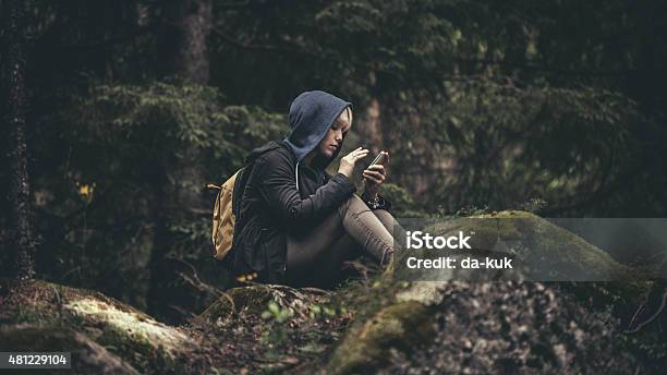 Foto de Viajante De Mochila Sentado Na Floresta E Segurando Um Smartphone e mais fotos de stock de Telefone celular