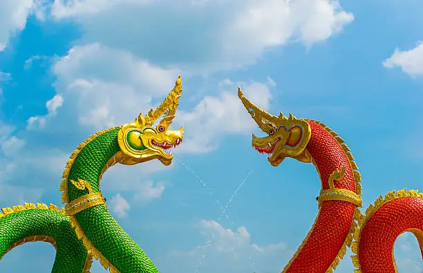 red and green dragon and Naga statue at Thai temple with blue sky and cloud