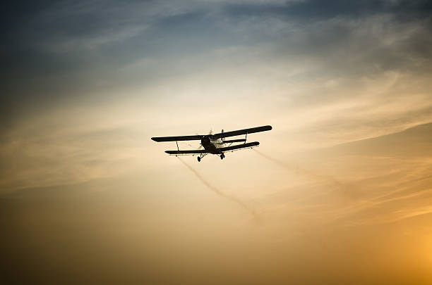 Airplane flying in the sky spraying mosquitoes stock photo