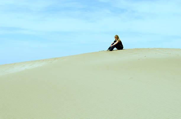 istock girl sitting on top of a dune 481238364