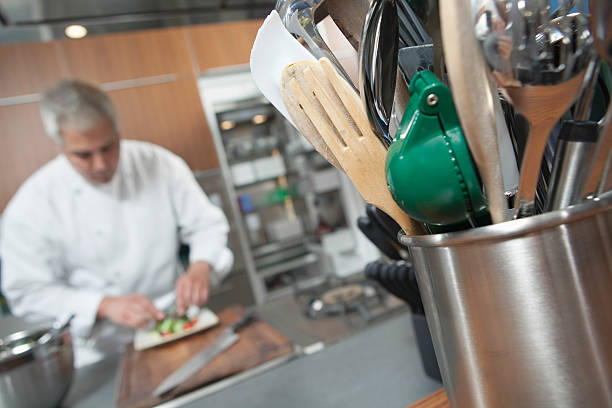 Male chef working with focus on utensil holder in foreground