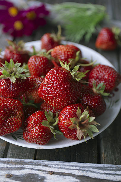 istock strawberries on white plates, on old gray wood table 481243400