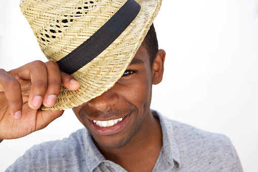 Close up portrait of a cheerful young man smiling with hat