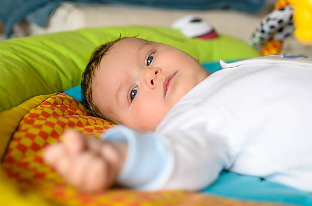 istock Cute baby boy is lying on colourful carpet 481251237