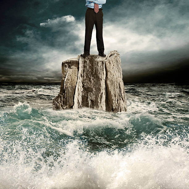 in piedi sulla roccia nel mare - storm sea business uncertainty foto e immagini stock
