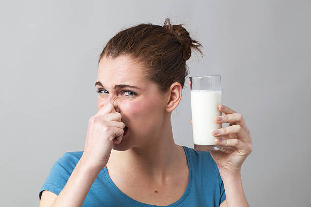 istock 20s girl holding her nose to avoid drinking milk 481251930