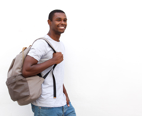 Portrait of a happy african american college student walking on isolated white background