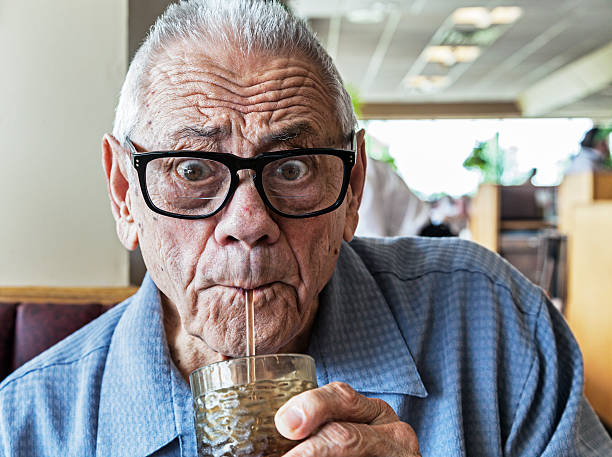 Funny Elderly Man Drinking With Straw An humorous elderly man with a wide-eyed, surprised facial expression is drinking water - or something even better - through a drinking straw. drinking straw funny stock pictures, royalty-free photos & images