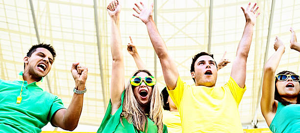 Excited Brazilian soccer supporters cheer their team at stadium A  group of extremely excited Brazilian soccer supporters waving in support of their team at a soccer match, perhaps taking part in a group Mexican wave. doing the wave stock pictures, royalty-free photos & images