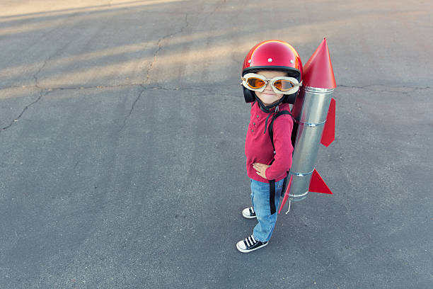 junge gekleidet in einen roten rocket anzug auf asphalt - stuntman stock-fotos und bilder