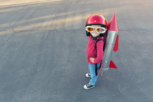 istock Young boy dressed in a red rocket suit on blacktop 481259115