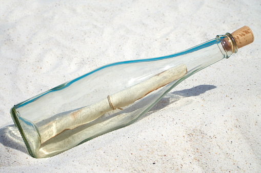 Message in a glass bottle lies on the sand beach
