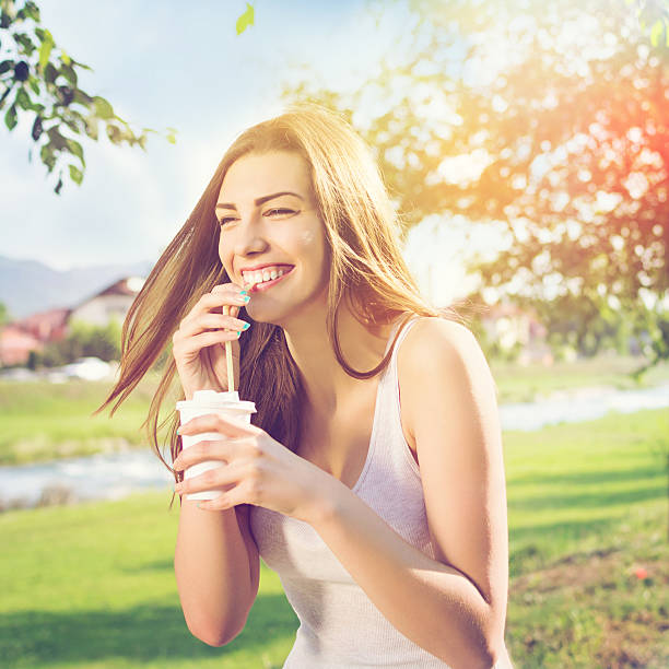 Bella felice giovane donna bere il caffè nel parco - foto stock