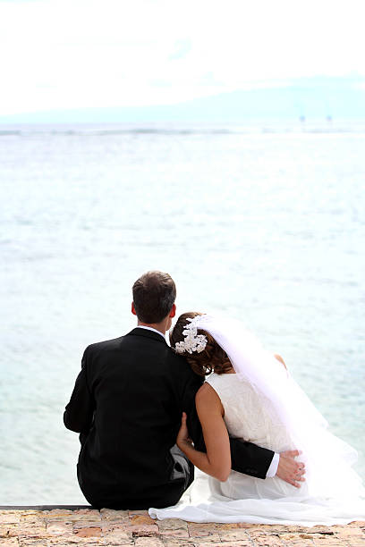 istock romantic newlywed couple sitting on seashore 481281914