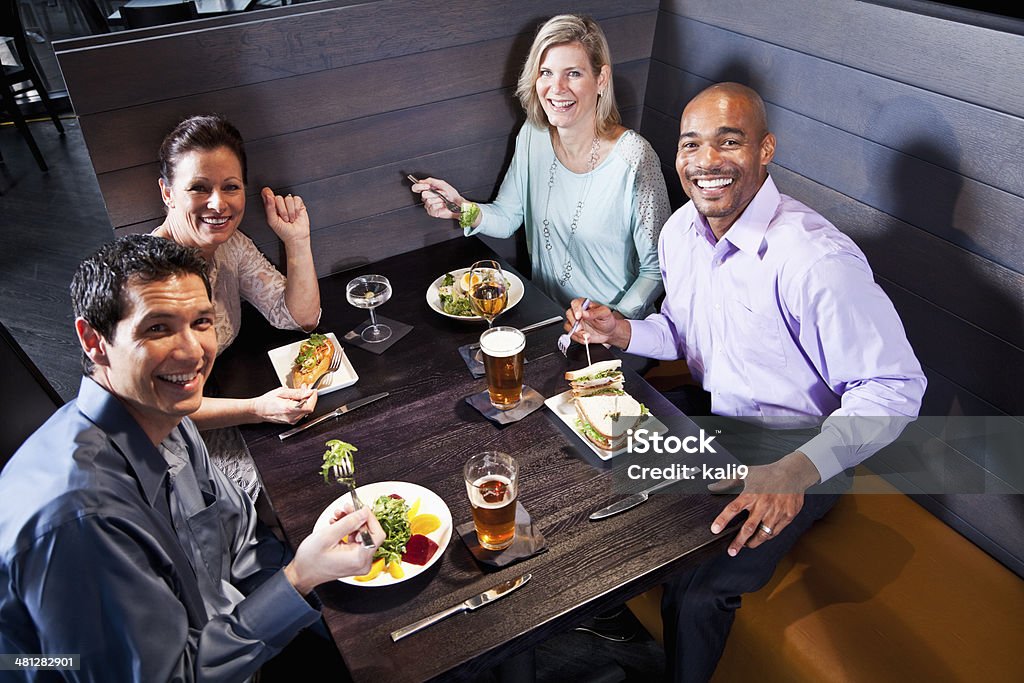 Two couples eating in a restaurant Two multi-ethnic couples eating, drinking and talking in restaurant. 30-39 Years Stock Photo