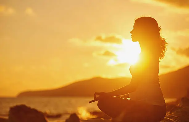 Photo of Pregnant woman practicing yoga in lotus position on beach