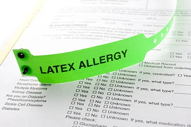 A latex allergy patient bracelet on top of a hospital questionnaire paperwork