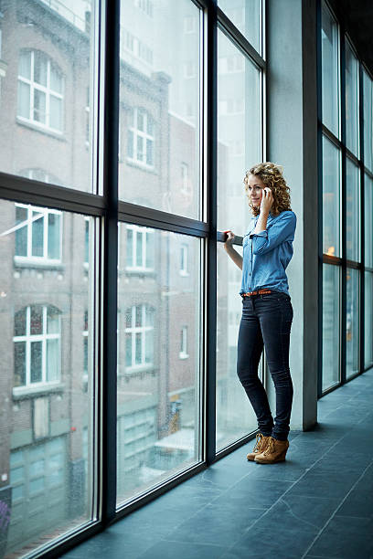 casually dressed business woman on the phone - full length windows fotografías e imágenes de stock