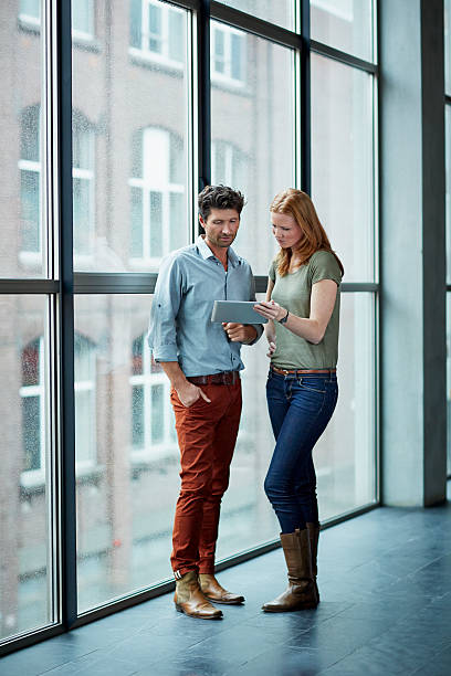 two coworkers having a casual discussion - full length windows stock-fotos und bilder