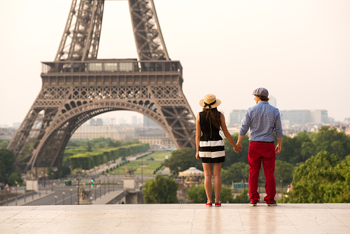 Couple dressed in traditional French fashion holding hands at the Eiffel Tower