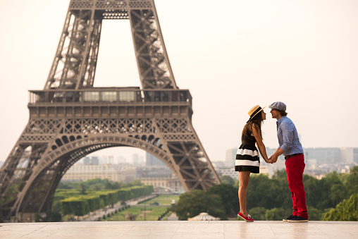 Couple dressed in traditional French fashion kissing at the Eiffel Tower