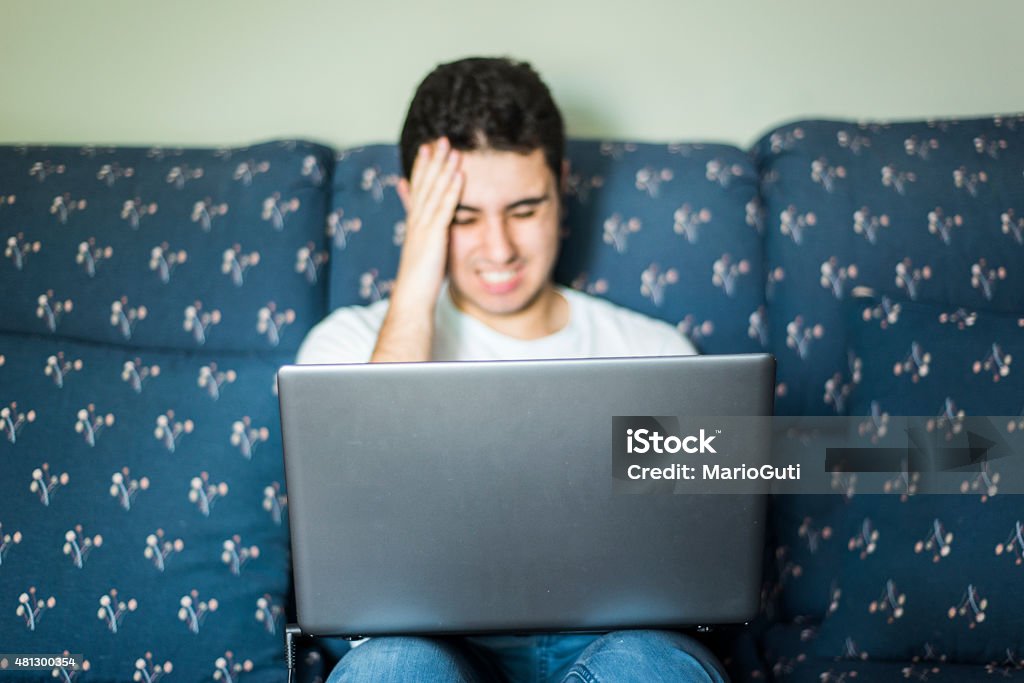 Headache from laptop screen A young man suffering a headache from looking at the laptop screen for a too long time. 20-24 Years Stock Photo