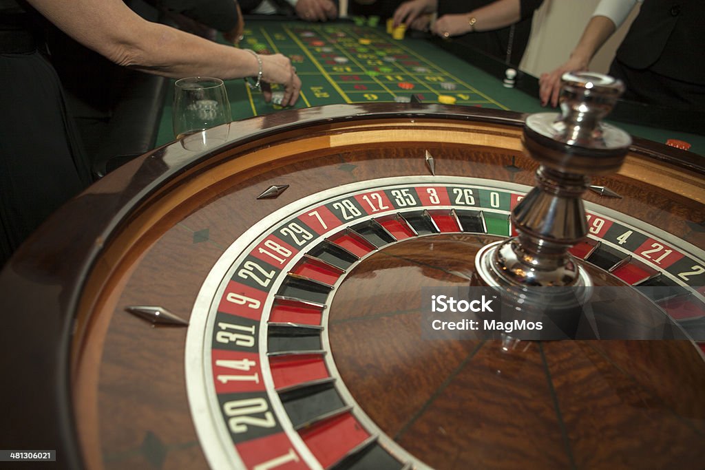 Casino Roulette  Wooden Wheel Green cloth on the roulette table. Placing chips in casino Addiction Stock Photo