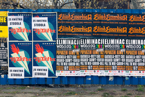 Warsaw, Poland - April 6, 2015: A fence along a city street in Warsaw covered with posters marketing various concerts and festivals.