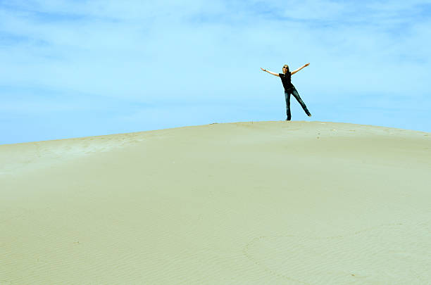 istock girl standing on top of a dune 481312140