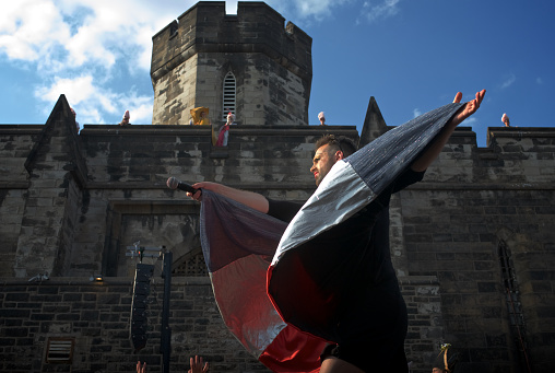 Philadelphia, PA, USA - July 11, 2015; The Bearded Ladies Artistic Director John Jarboe in his roll as French Icon Édith Piaf is seen consulting the 'French Bourgeoisie' about the destiny of Marie Antoinette (seen standing atop of the wall). The crowds gathered in attendance of the free event play the roll of French Bourgeoisie during the annual Bastille Day celebrations outside the historic Eastern State Penitentiary in Philadelphia. (photo by Bastiaan Slabbers)