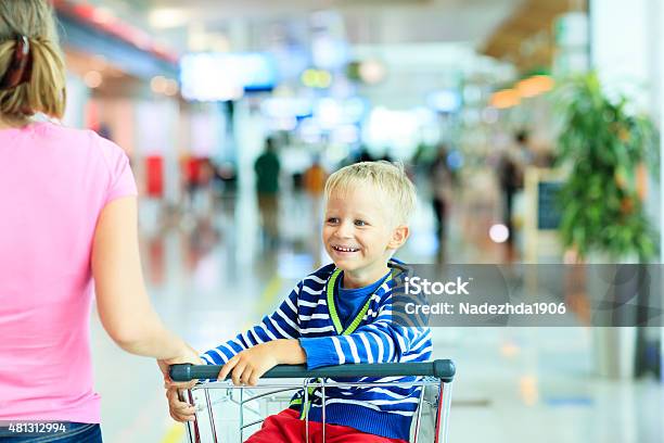 Happy Cute Boy At Airport Riding On Luggage Cart Stock Photo - Download Image Now - 2015, Activity, Adult