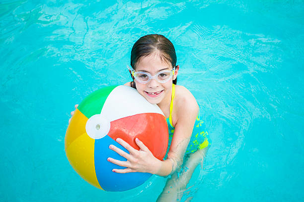 mignonne petite fille jouant avec un ballon de plage de la piscine - beach ball swimming pool ball child photos et images de collection