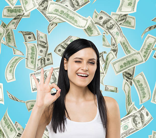 istock Brunette woman shows ok sign. Dollar notes are falling down 481326290