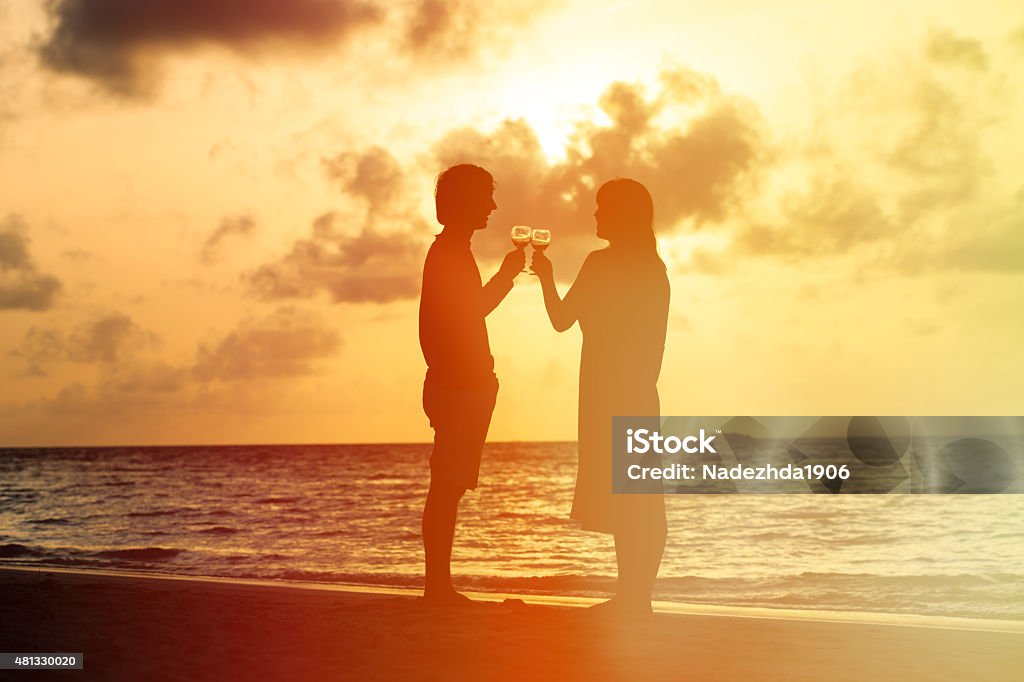 Silhouette of couple drinking wine at sunset Silhouette of couple drinking wine at sunset beach 2015 Stock Photo