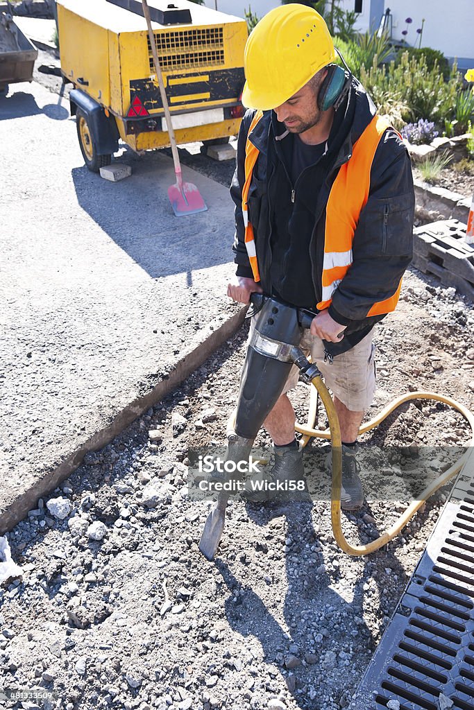 Road Worker with Jackhammer Shot of a hard working road construction worker using a jackhammer, a very hard, noisy and dusty work. Jackhammer Stock Photo