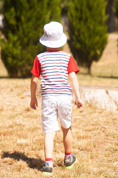 istock Boy walking away in  sunny park 481334090